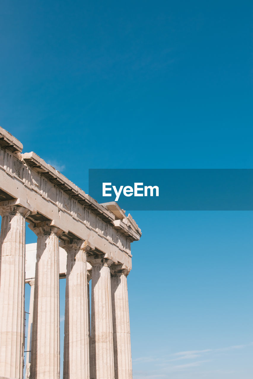 Low angle view of acropolis against clear sky during sunny day