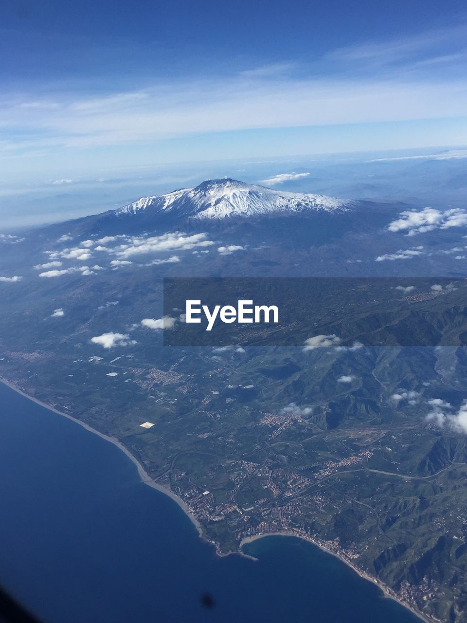 AERIAL VIEW OF SNOWCAPPED MOUNTAINS AND SEA AGAINST BLUE SKY