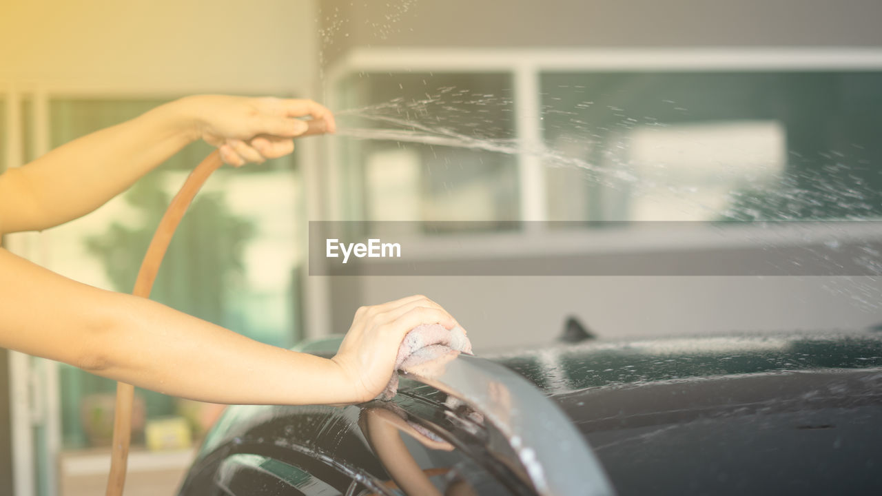 Cropped hands of woman cleaning car