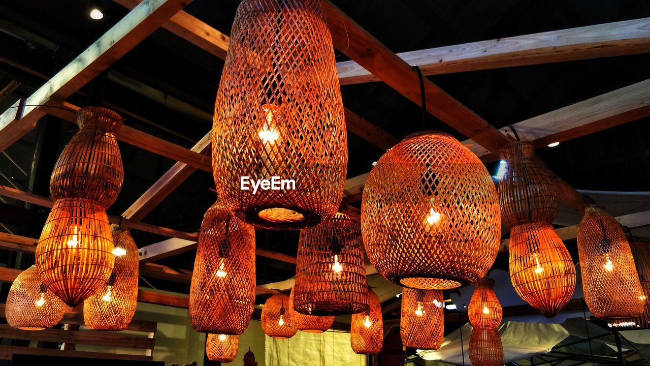 LOW ANGLE VIEW OF ILLUMINATED LANTERNS HANGING AT NIGHT