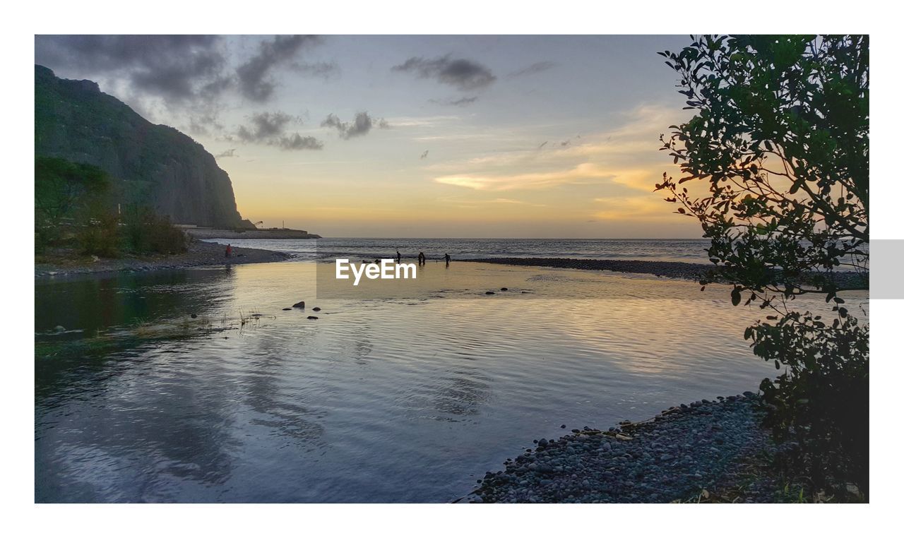 SCENIC VIEW OF BEACH AGAINST SKY AT SUNSET