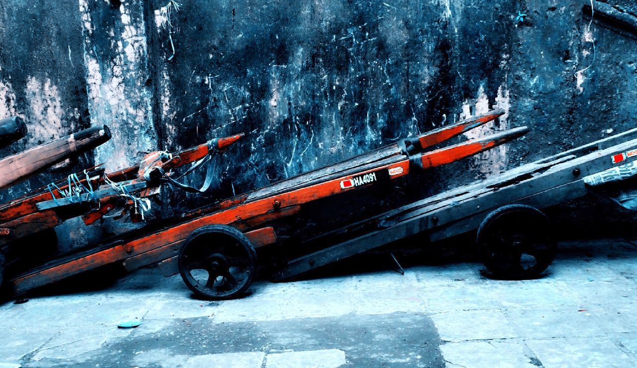 Market push cart parked in front of weathered wall