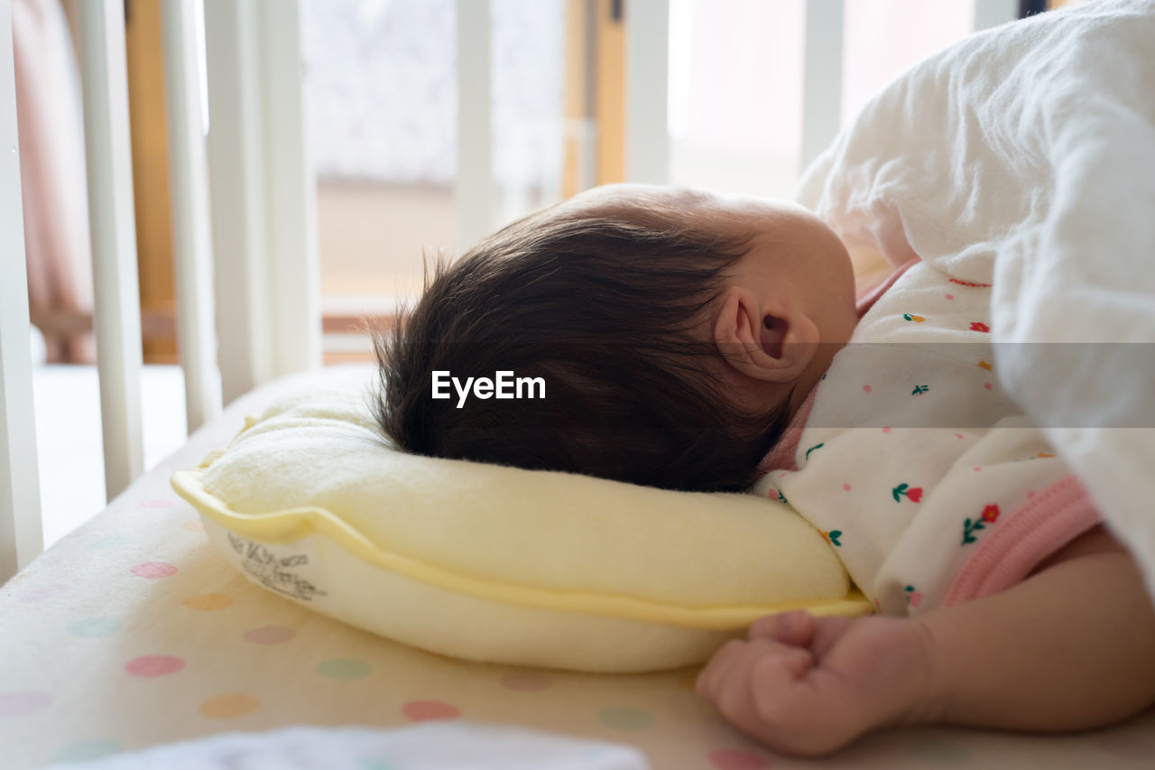 Close-up of cute baby girl sleeping on bed at home