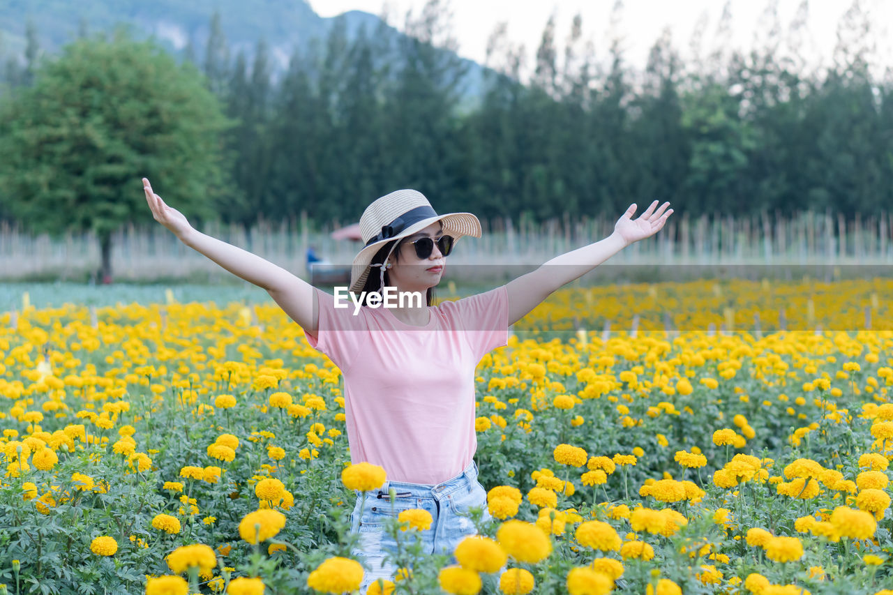 Woman wearing sunglasses while standing by flowering plants