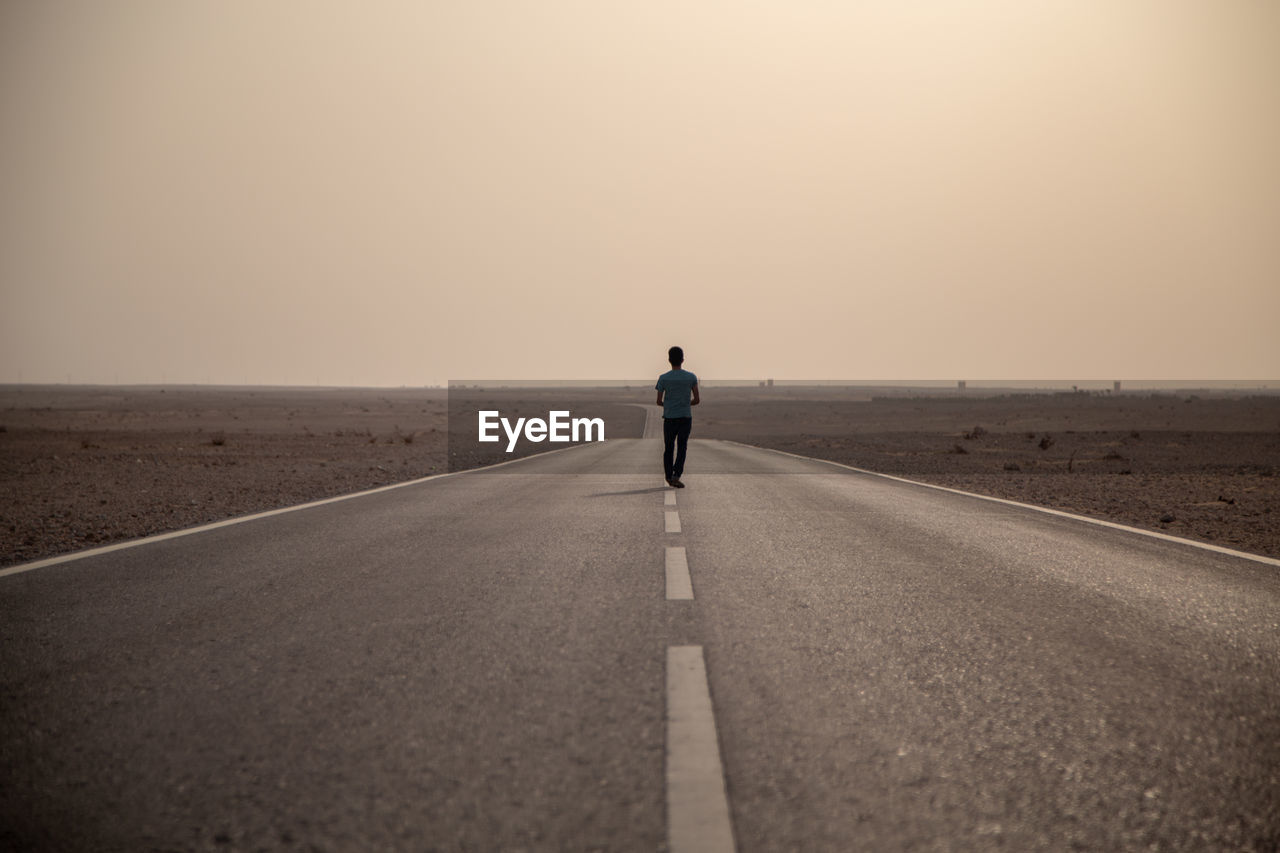 FULL LENGTH REAR VIEW OF MAN ON ROAD AGAINST SKY