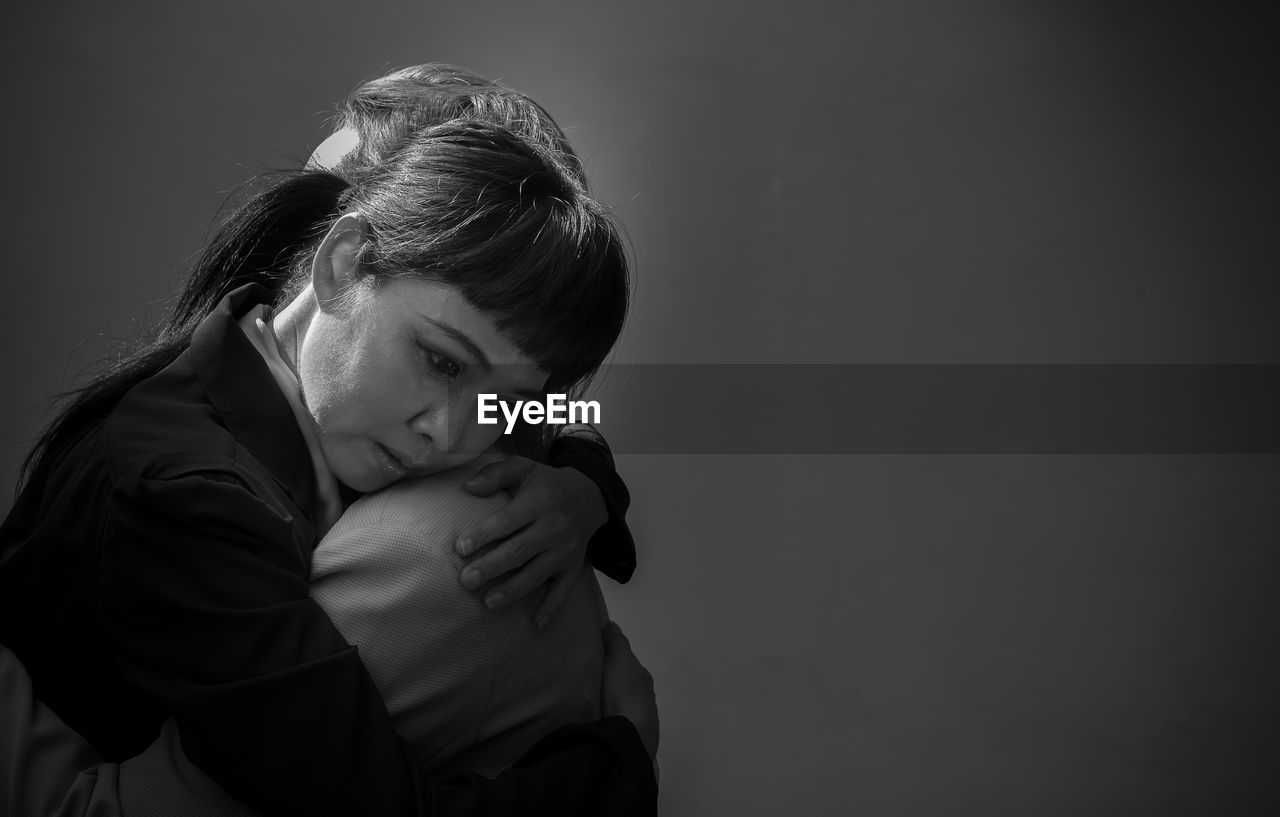 Lesbian couple embracing against black background