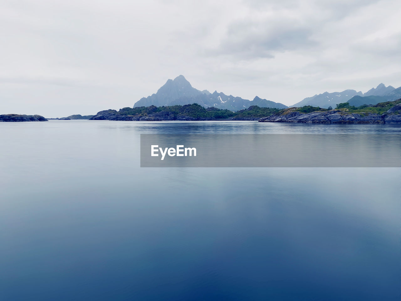 Scenic view of calm sea against sky and mountain