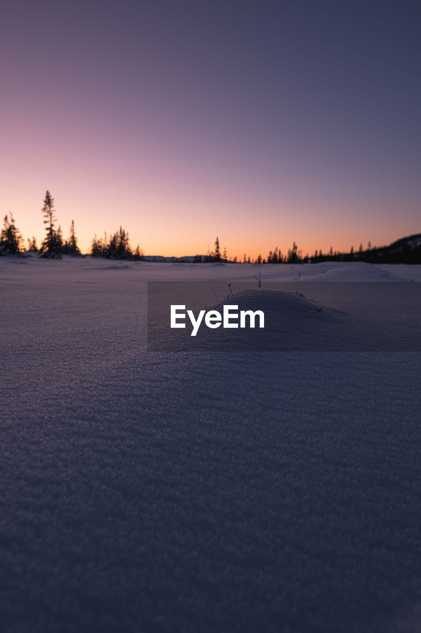 Scenic view of winter landscape against clear sky during sunset