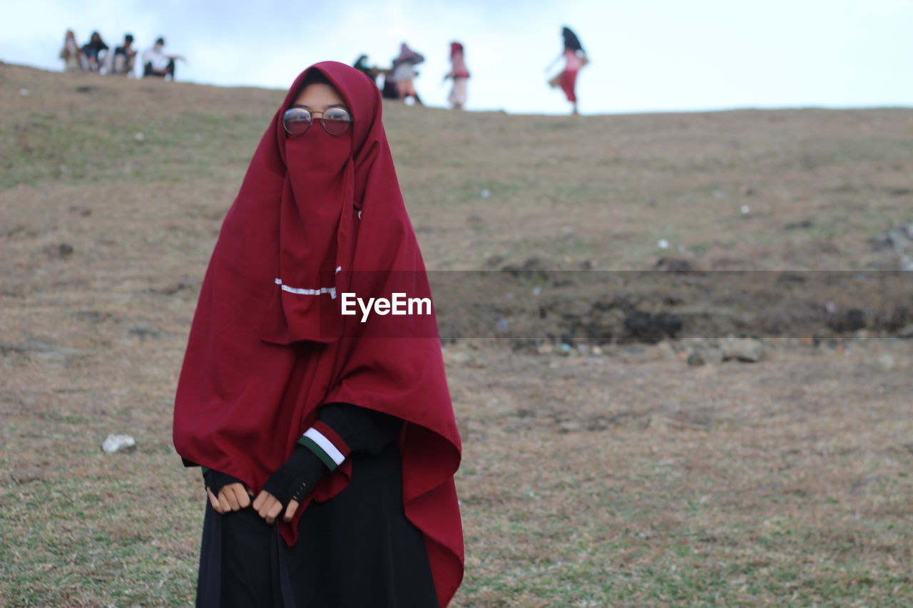 MIDSECTION OF WOMAN STANDING ON FIELD