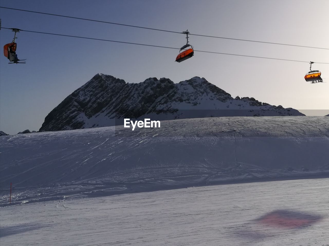 Overhead cable car over snowcapped mountains against sky