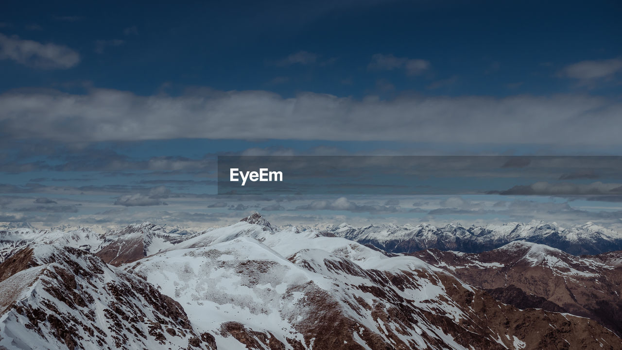 AERIAL VIEW OF SNOWCAPPED MOUNTAINS AGAINST SKY