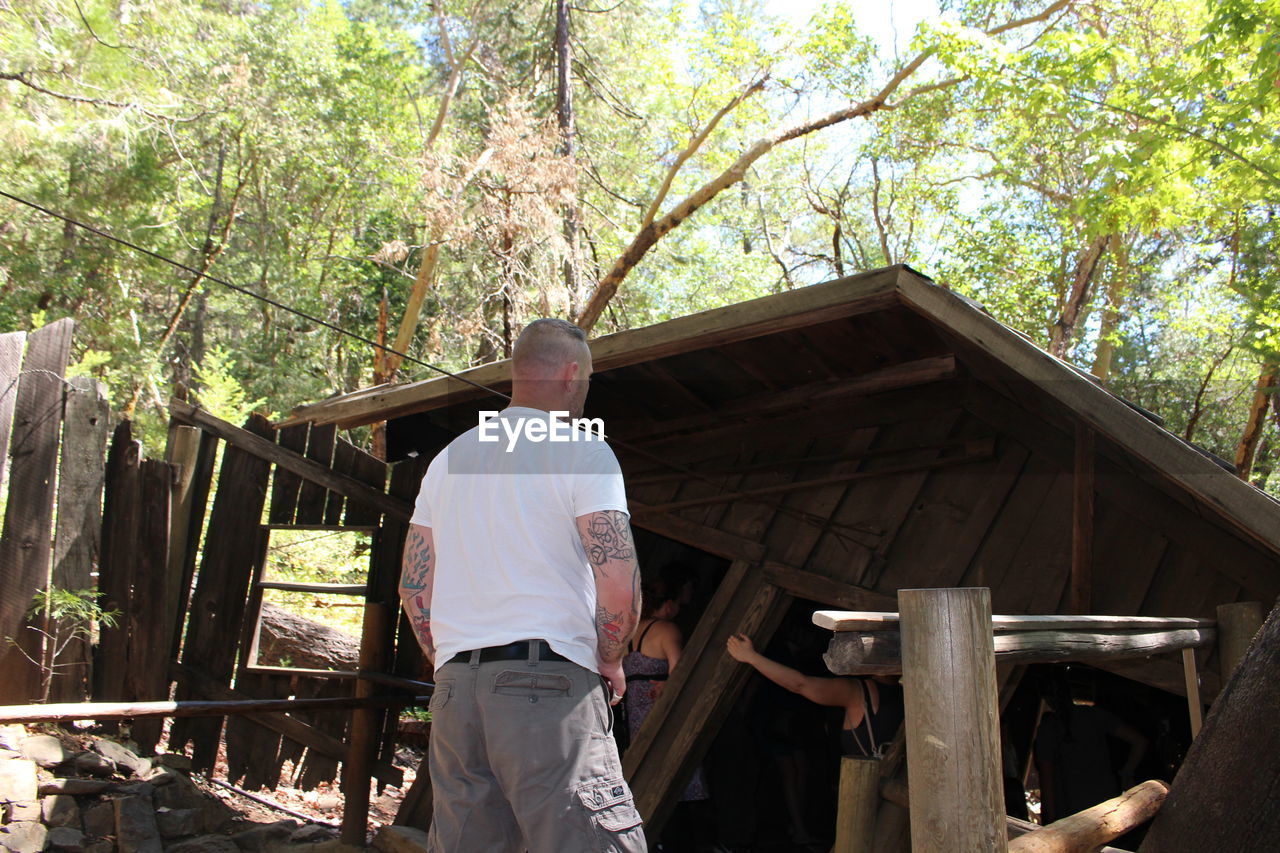 REAR VIEW OF MAN STANDING BY PLANTS