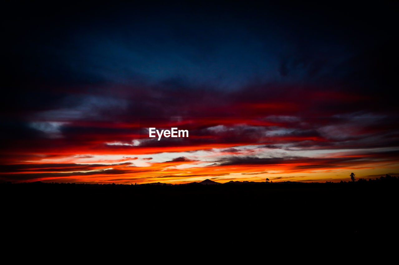 Scenic view of dramatic sky over silhouette landscape