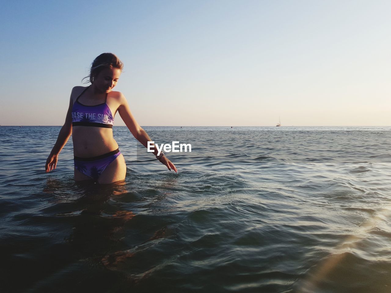 Woman in sea against sky during sunset