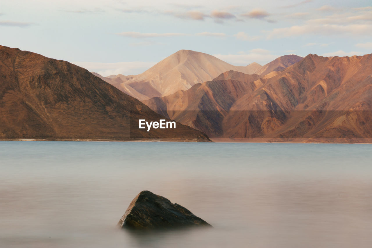 Scenic view of lake by mountains against sky