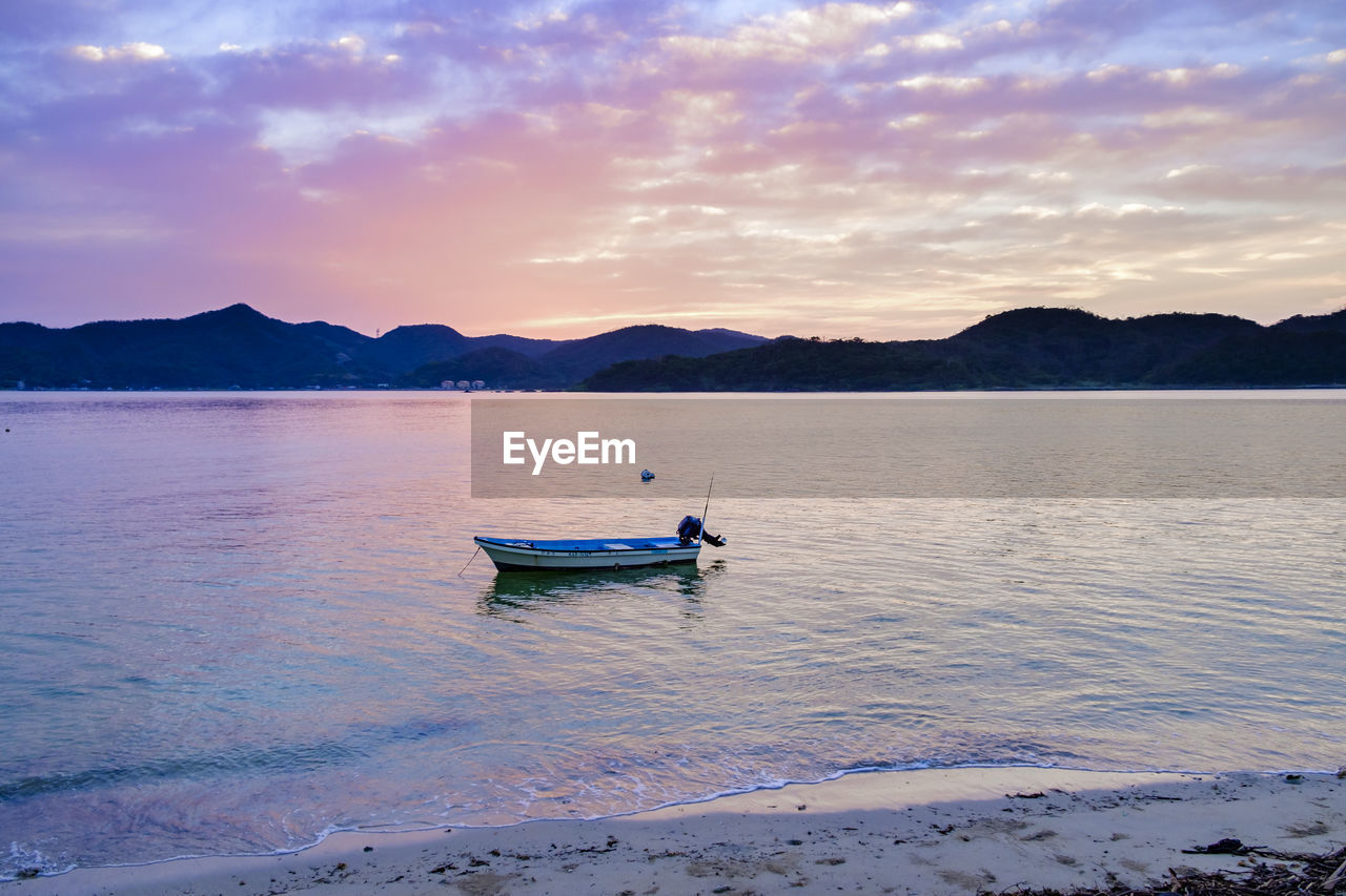 Boat in sea against sky during sunset