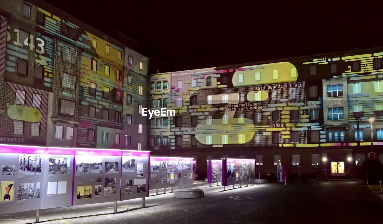 ILLUMINATED STREET AMIDST BUILDINGS AT NIGHT