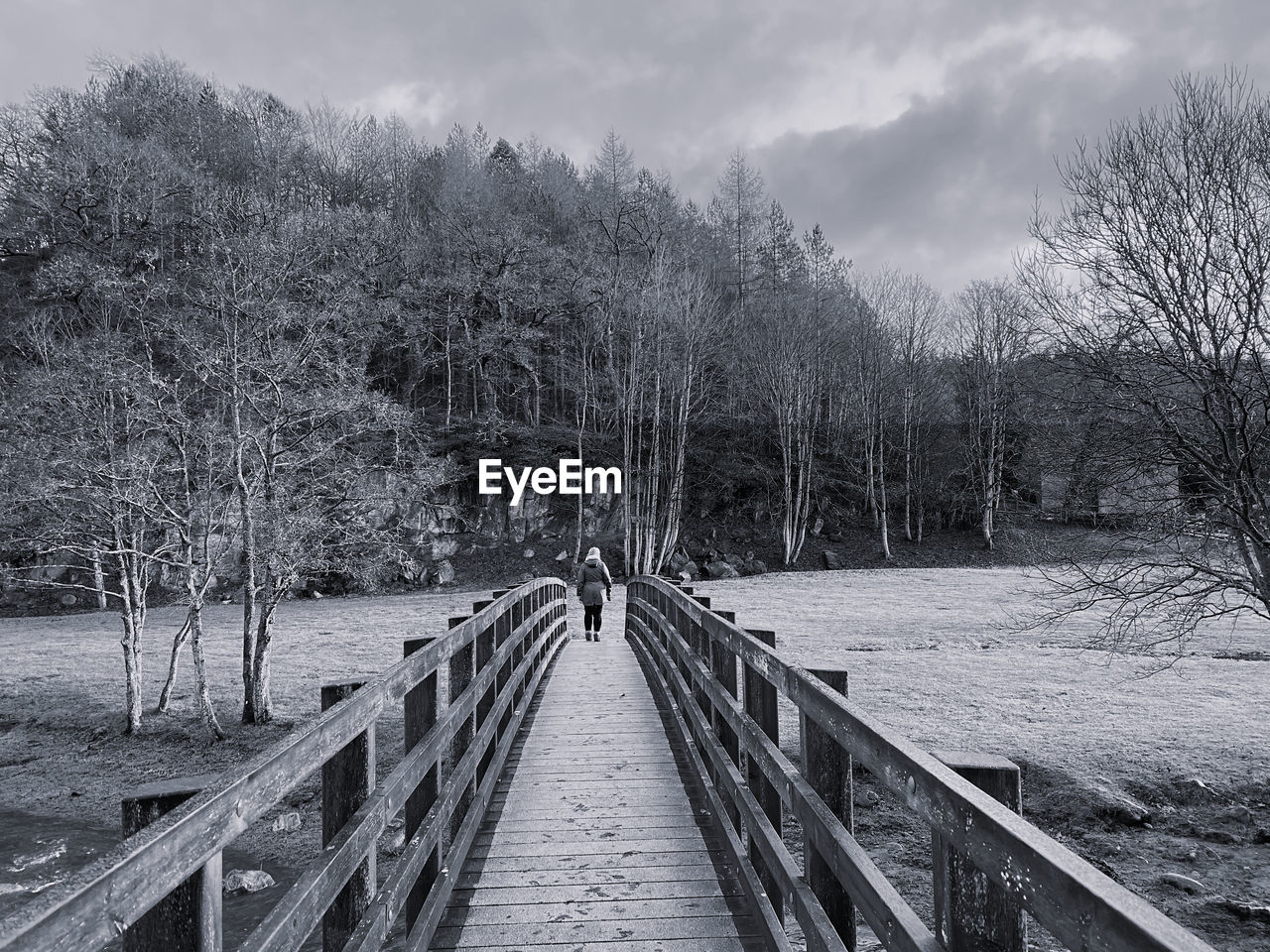 Black and white woman walking across a wooden bridge