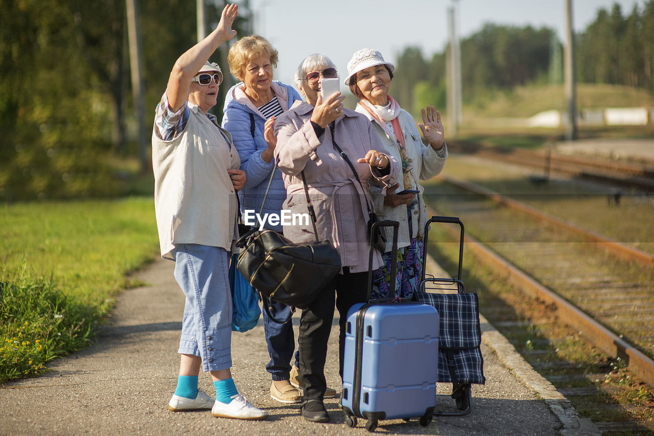 Group of senior women take a self-portrait on  platform waiting for  train  travel during a covid-19 