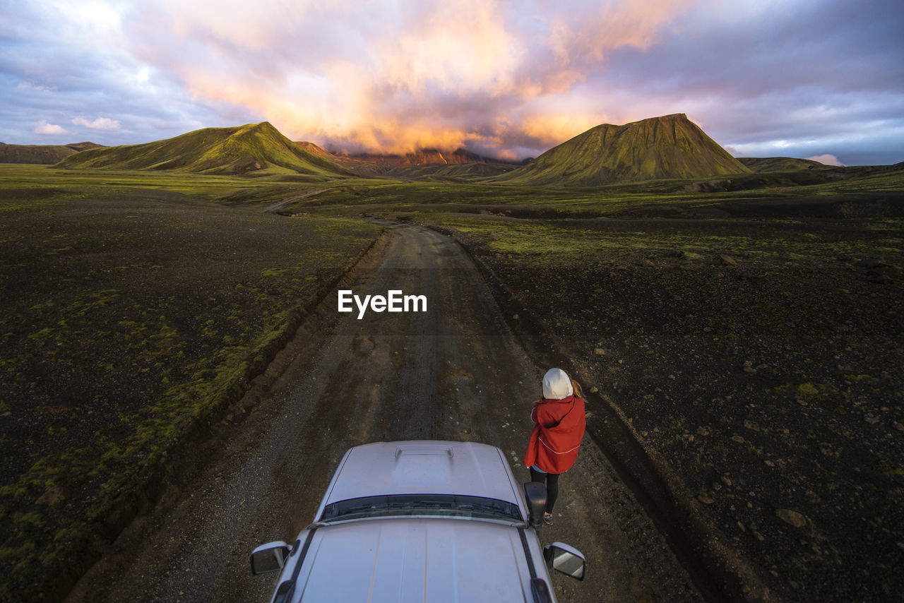 Photographer taking picture of sunset on mountains next to car