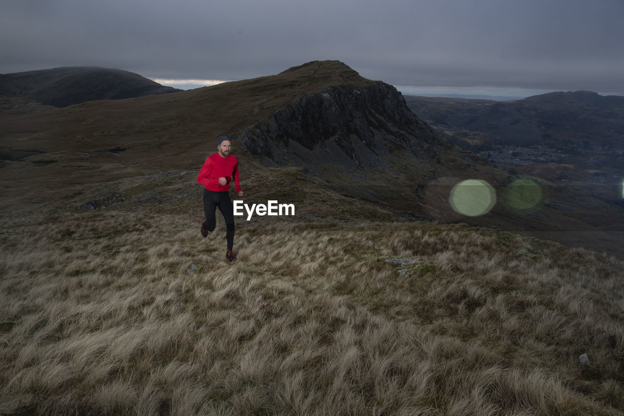 Determined man doing fell running on hill at dusk