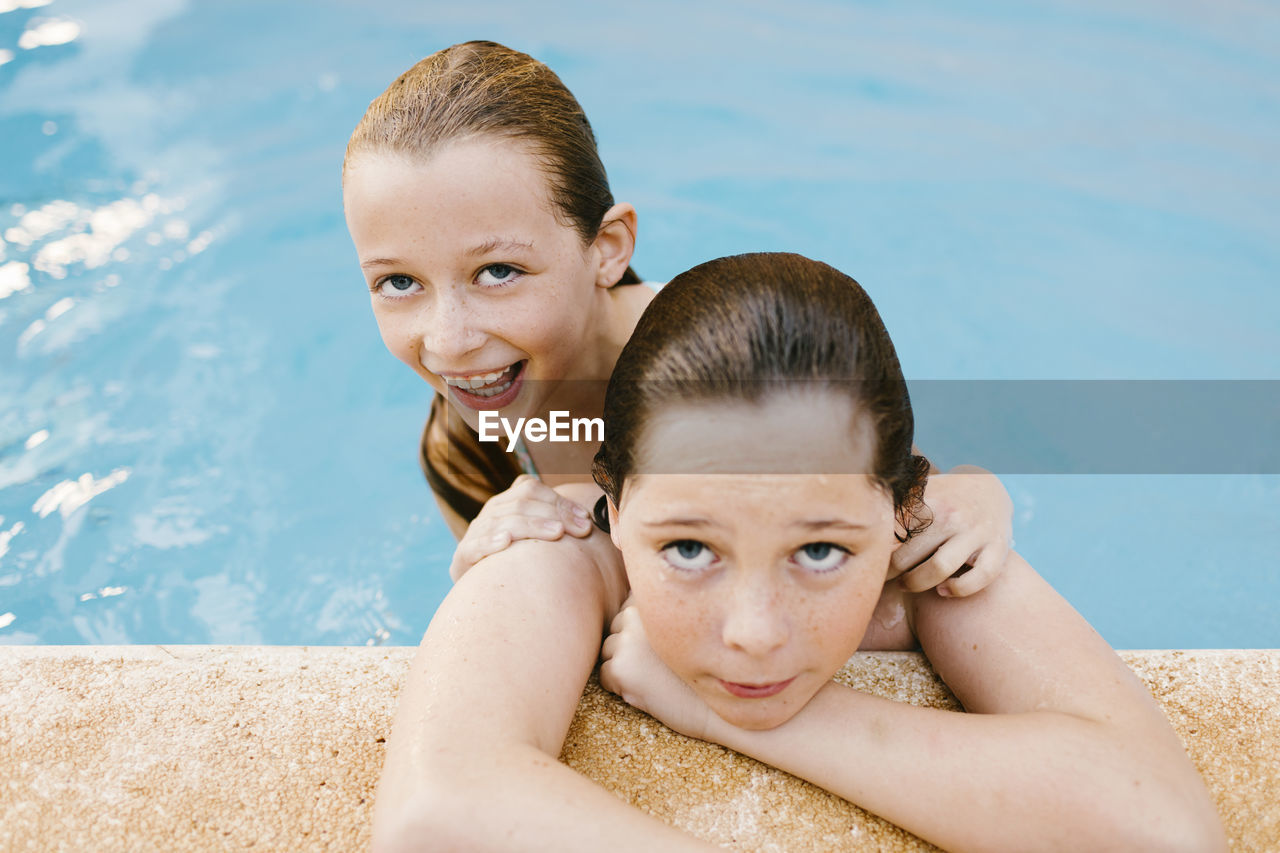 Smiling sister with brother in swimming pool