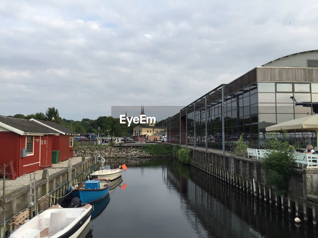 Boats moored in canal amidst buildings in city against sky