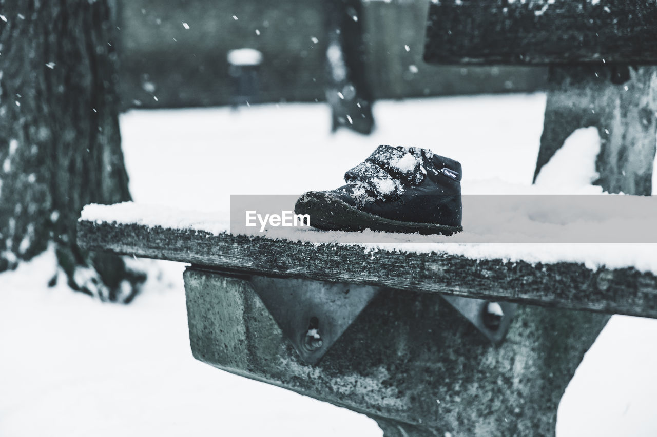 Close-up of snow covered shoe on park bench