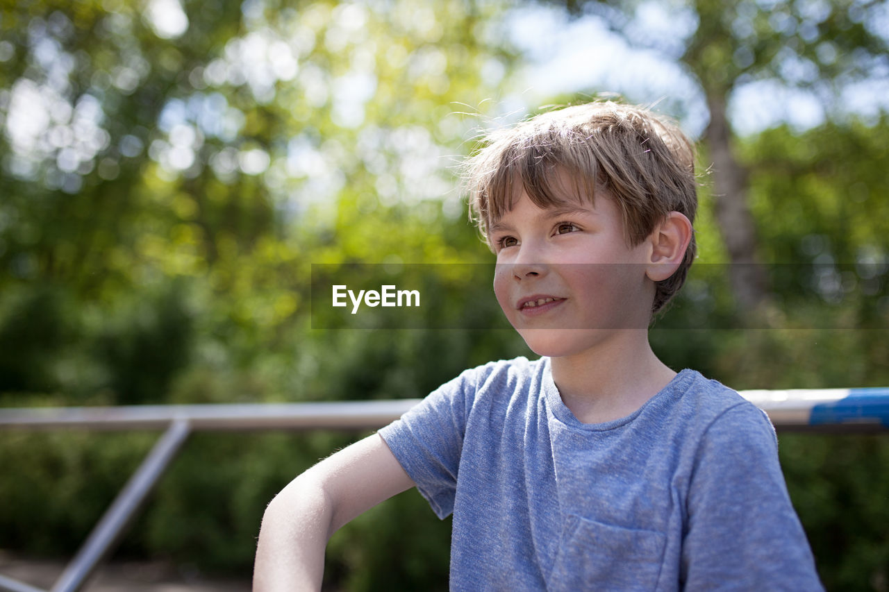 Close-up of boy smiling against trees