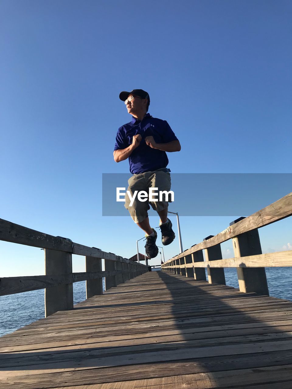 Man jumping on footbridge against clear sky