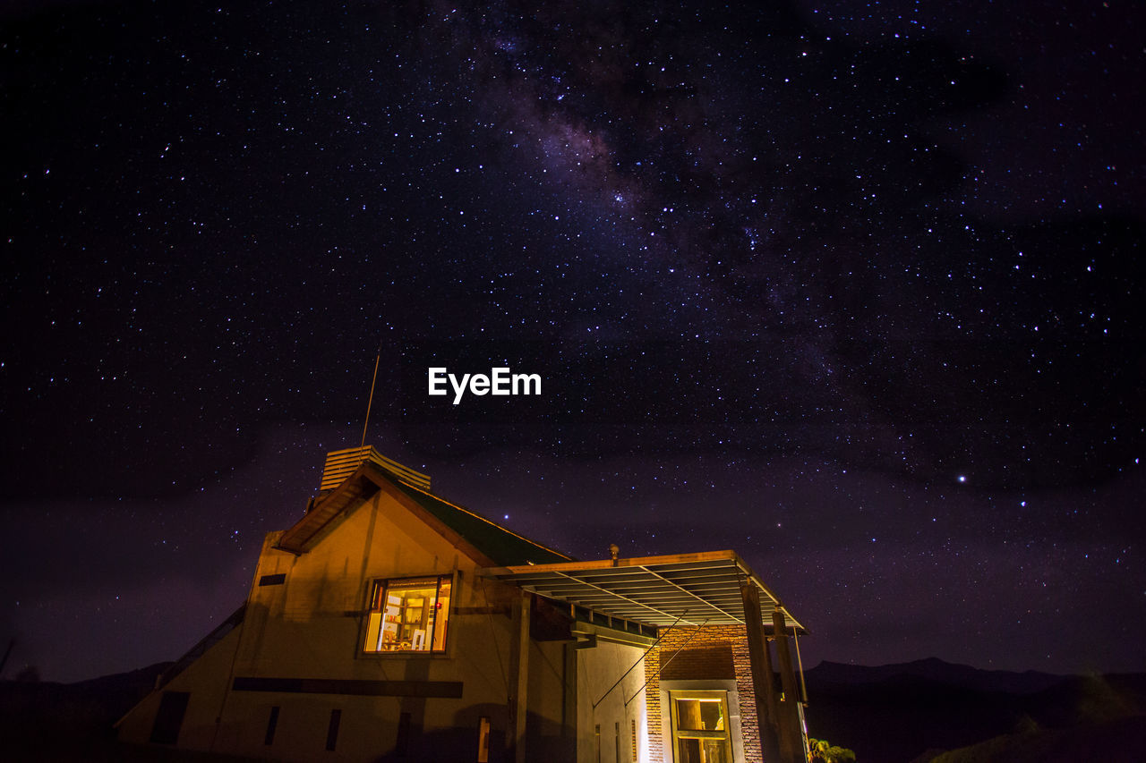 Illuminated house against star field