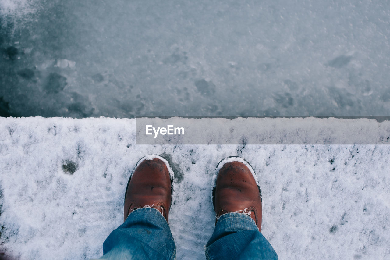 Low section of man standing on snow