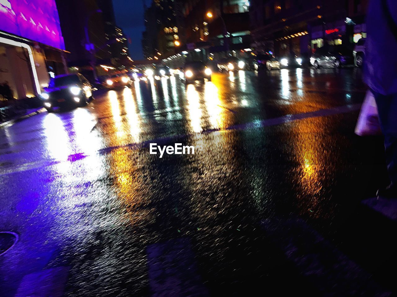 Illuminated vehicle headlights with reflection on wet city street