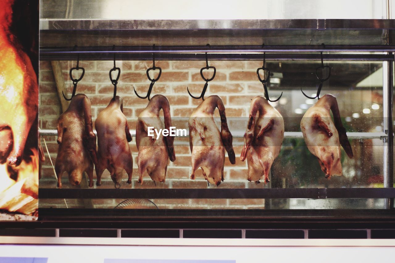 Duck meats hanging by hook on window display