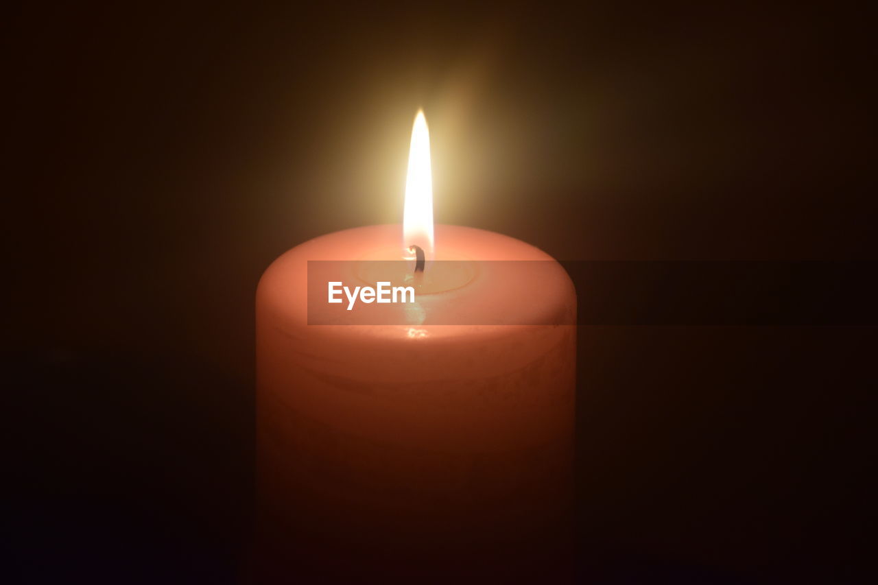 Close-up of lit candle in darkroom