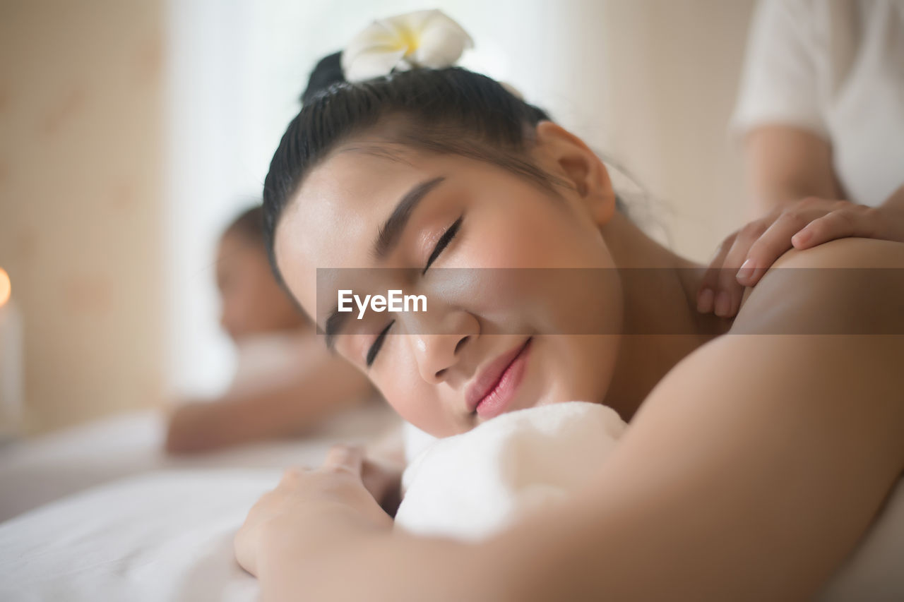 Smiling young woman being massaged on table in spa
