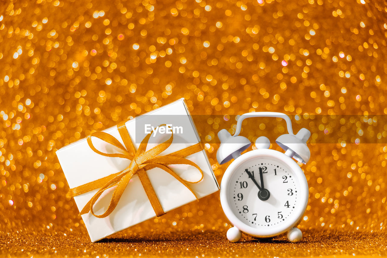 Christmas gift and alarm clock on a shining gold background. new year concept.