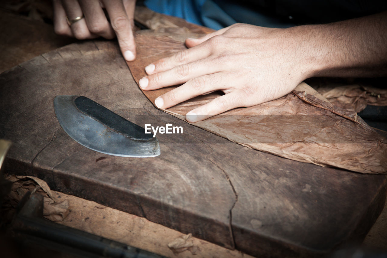 Midsection of worker making cigar