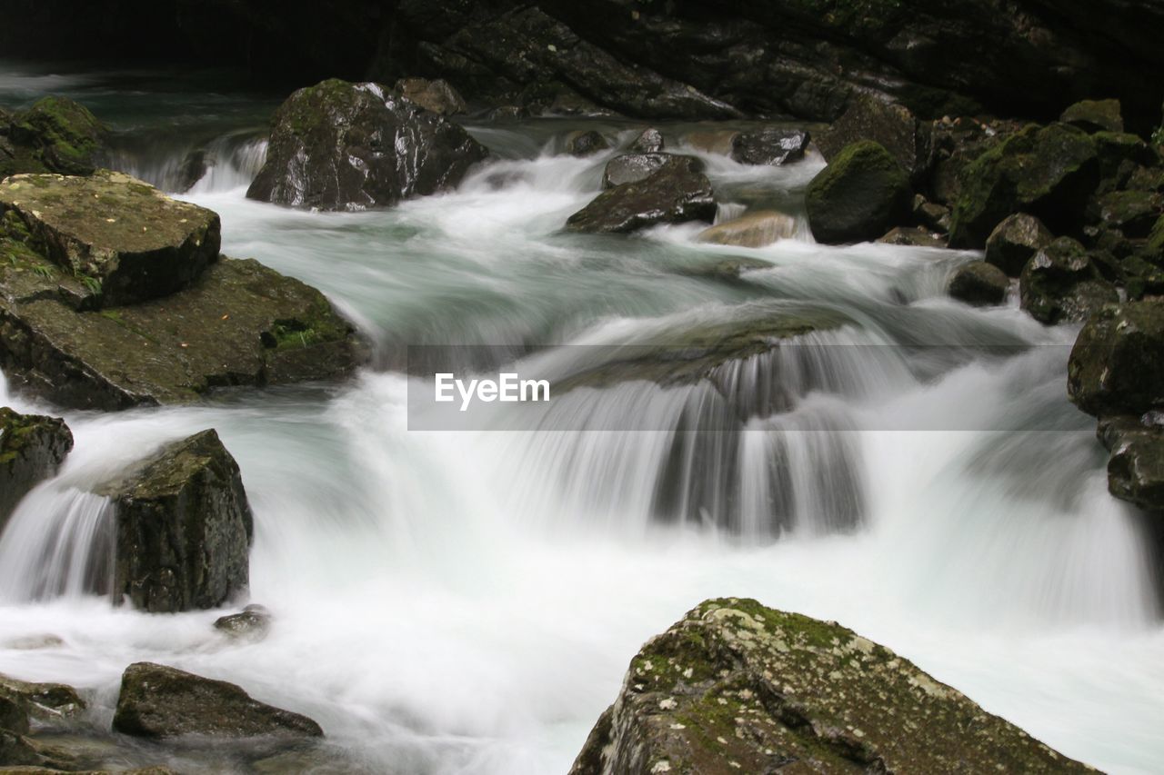 Scenic view of water streaming past rocks