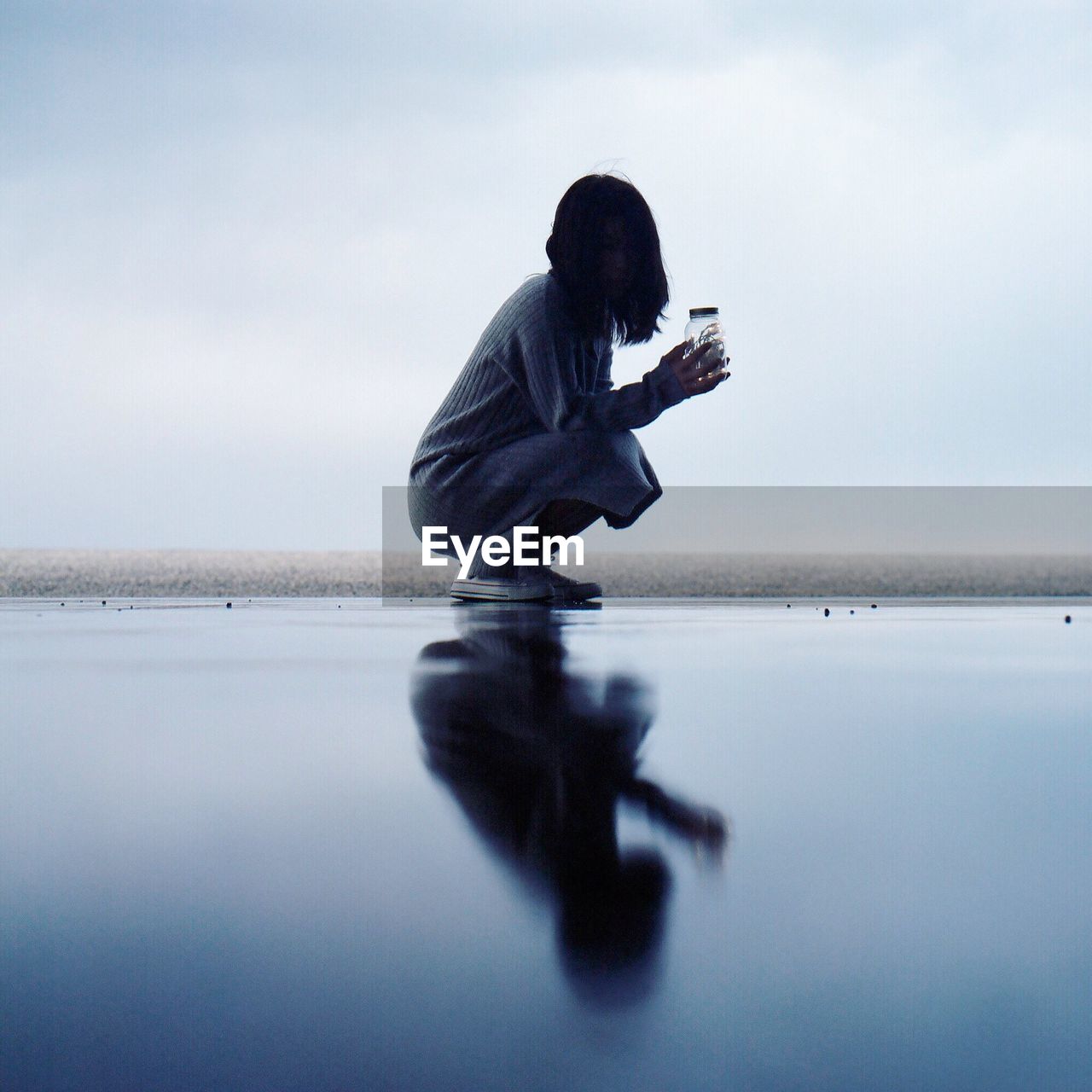 Side view of woman by sea against sky