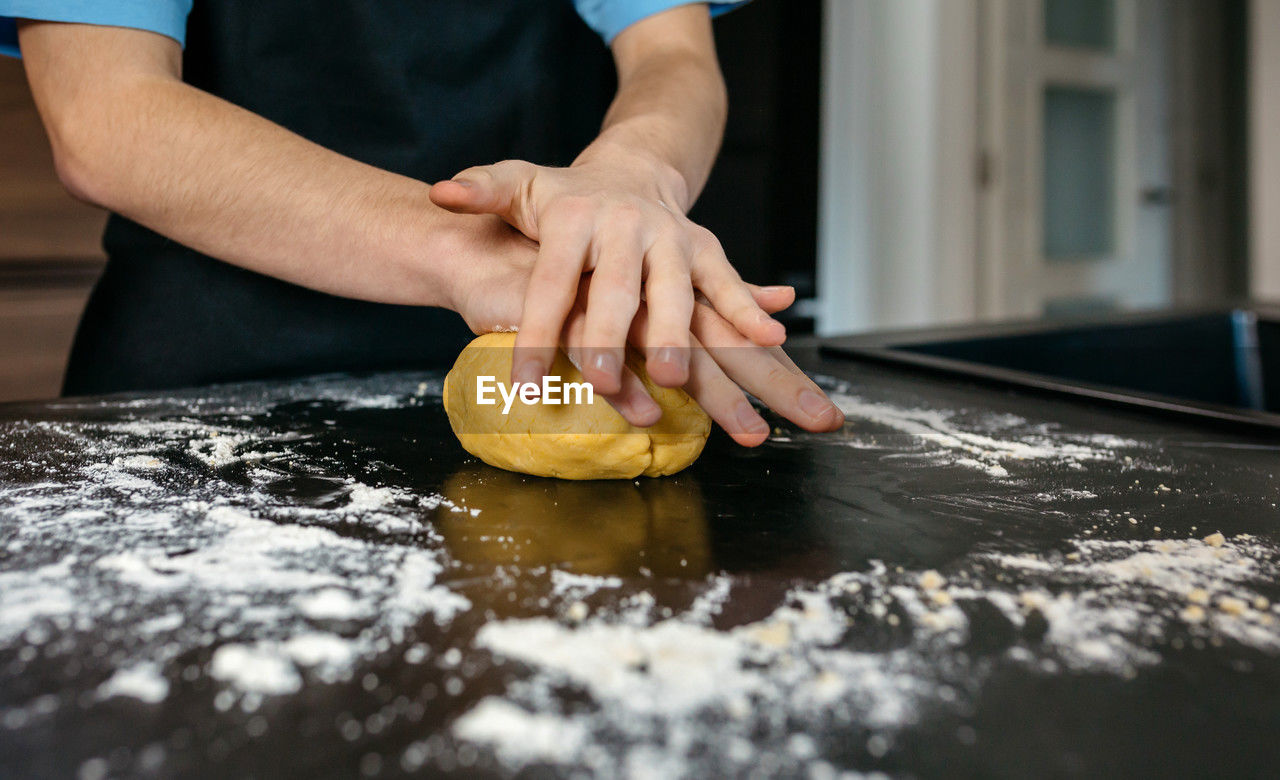 dough, hand, food, one person, food and drink, indoors, occupation, preparing food, adult, freshness, kitchen, flour, bakery, baker, midsection, cooking, making, baked, chef, working, baking bread, men, domestic room, skill, food and drink establishment, icing, selective focus, kneading, kitchen counter, store, raw food, holding, person, business, close-up, standing
