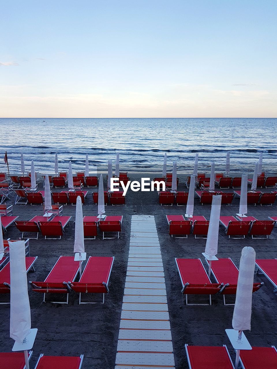 CHAIRS AND TABLES AT BEACH AGAINST CLEAR SKY