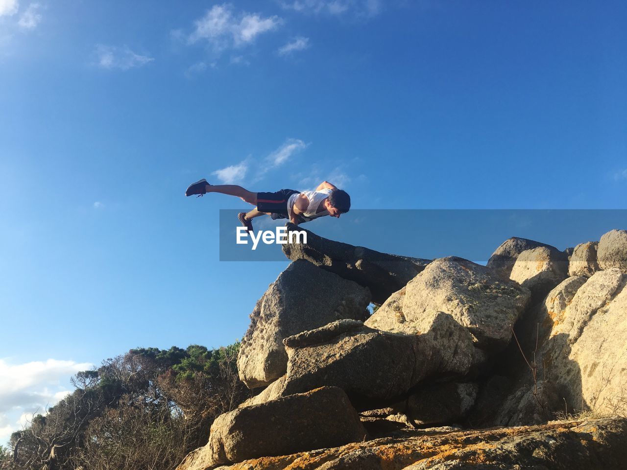 Low angle view of man balancing on rock against sky