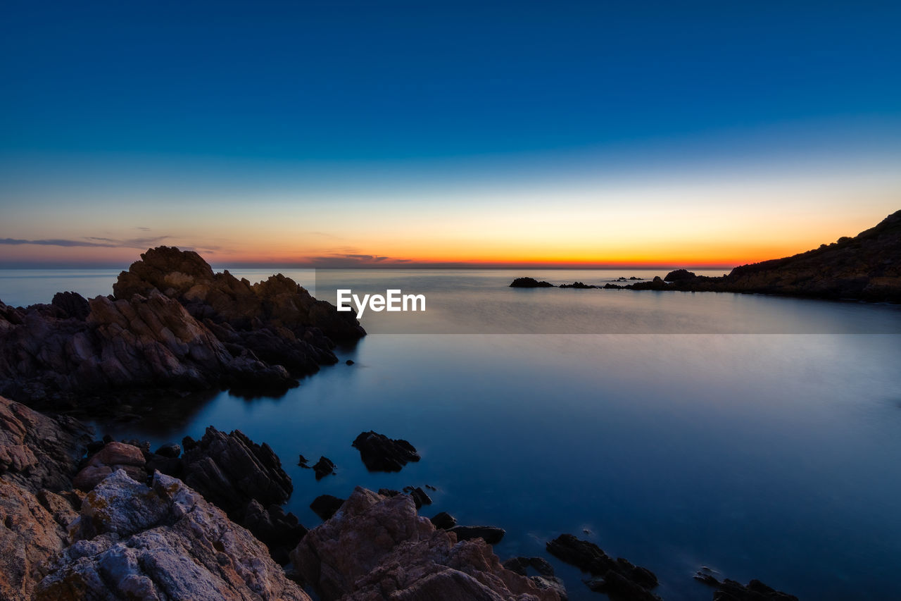 Scenic view of sea against sky at sunrise with rocks in the foreground