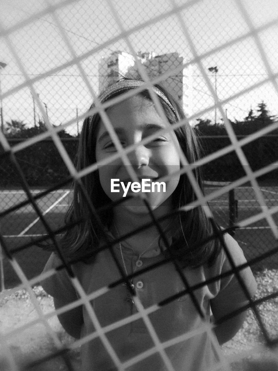 Portrait of smiling girl seen through chainlink fence