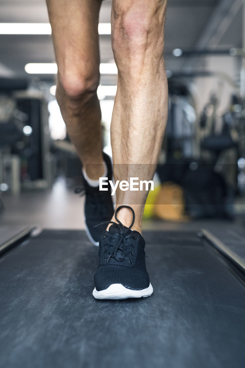 Legs of man on treadmills working out in gym