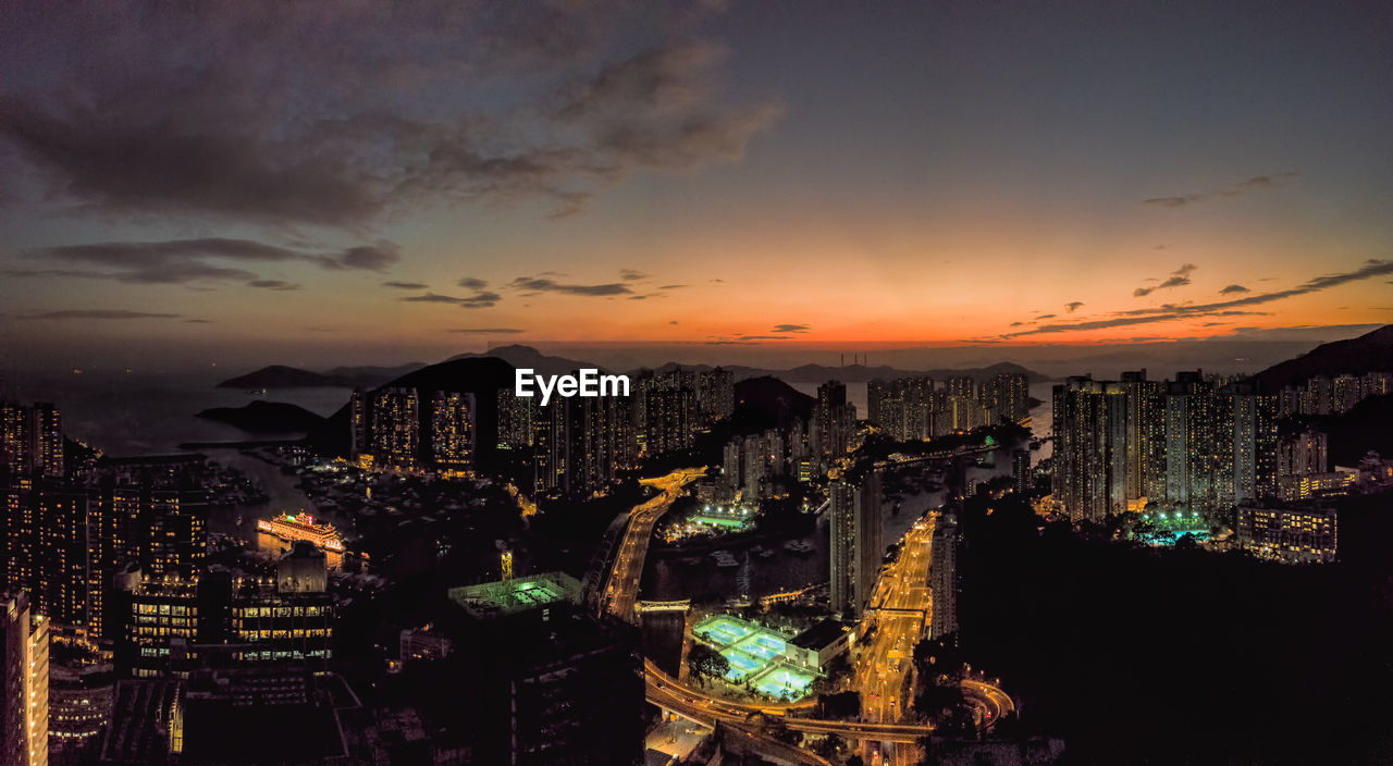 Illuminated cityscape against sky at sunset