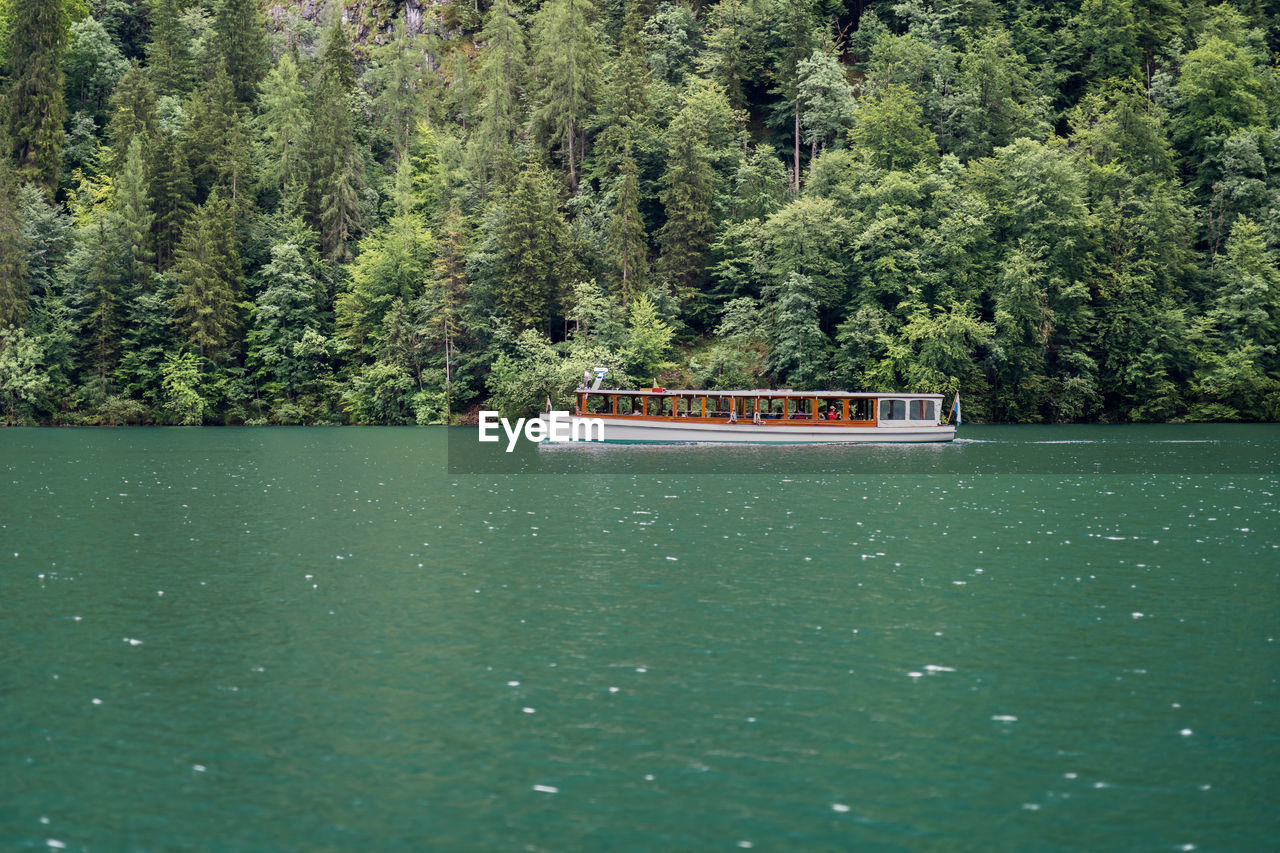 Boat sailing in lake against trees