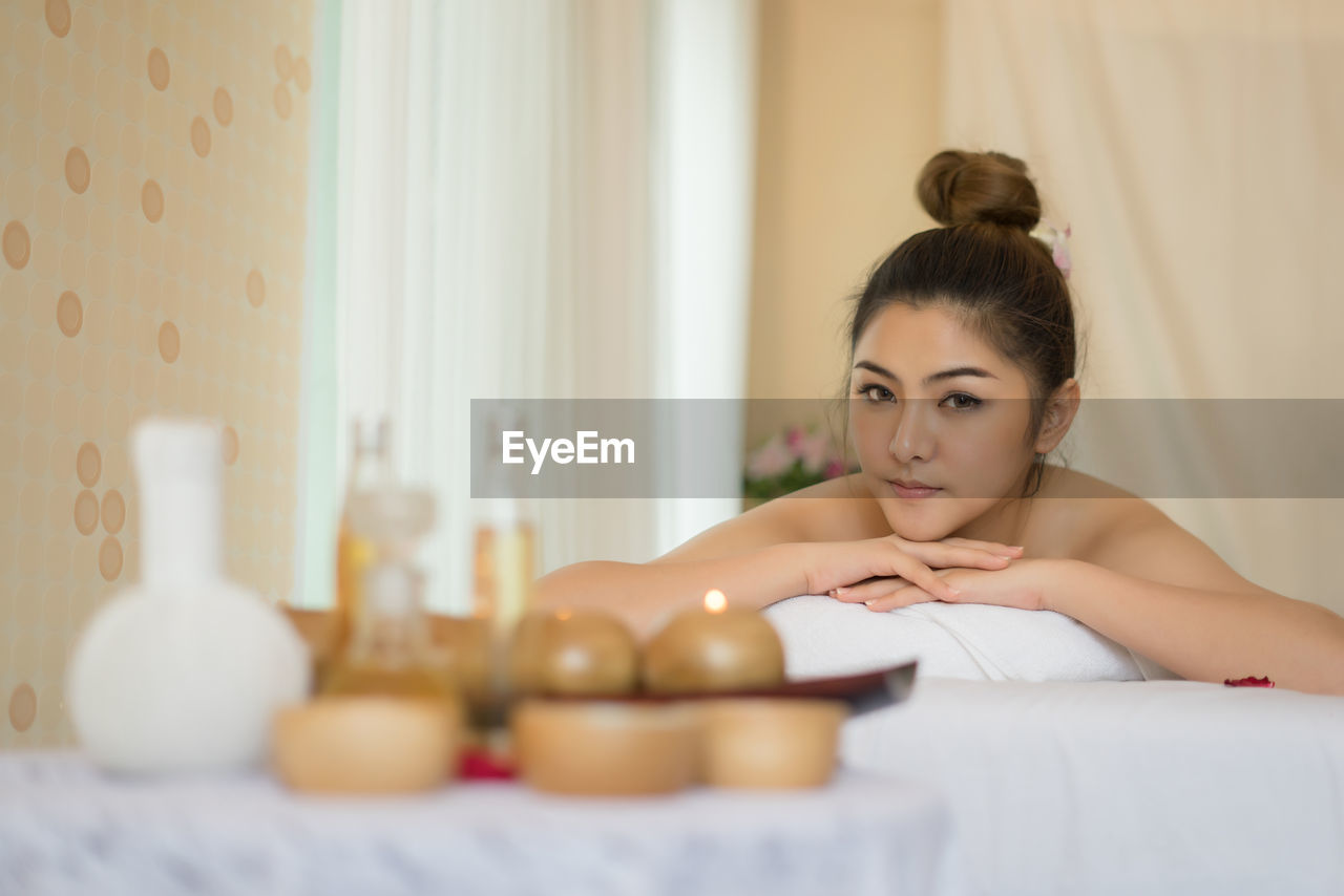 Portrait of young woman lying on massage table in spa