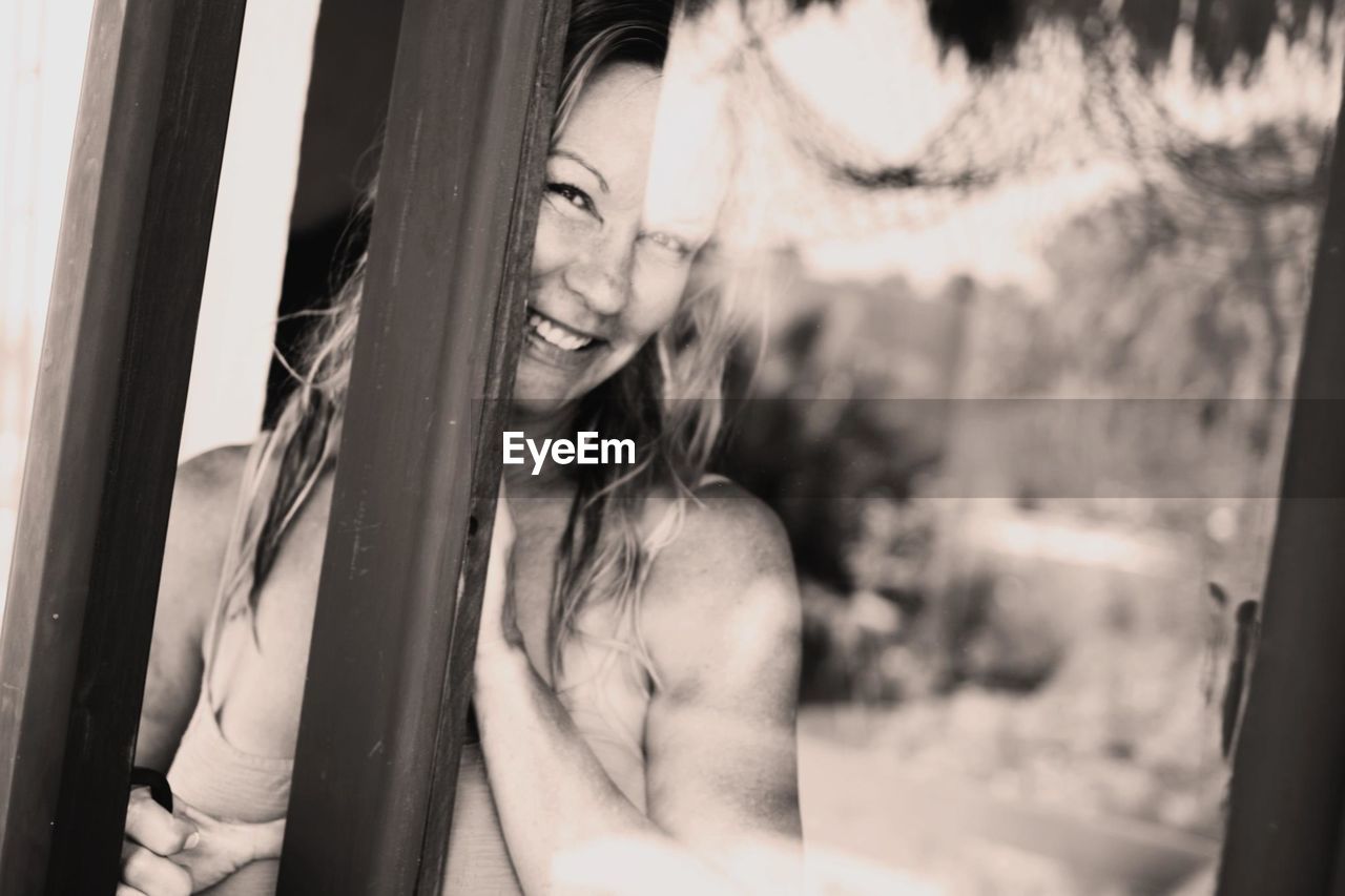Portrait of smiling happy woman seen through glass door